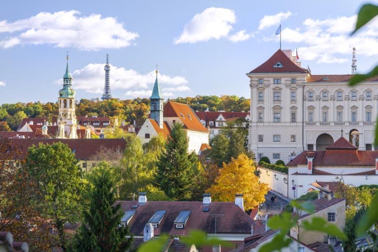 Prague City View with Historic Spire and Autumn Foliage
